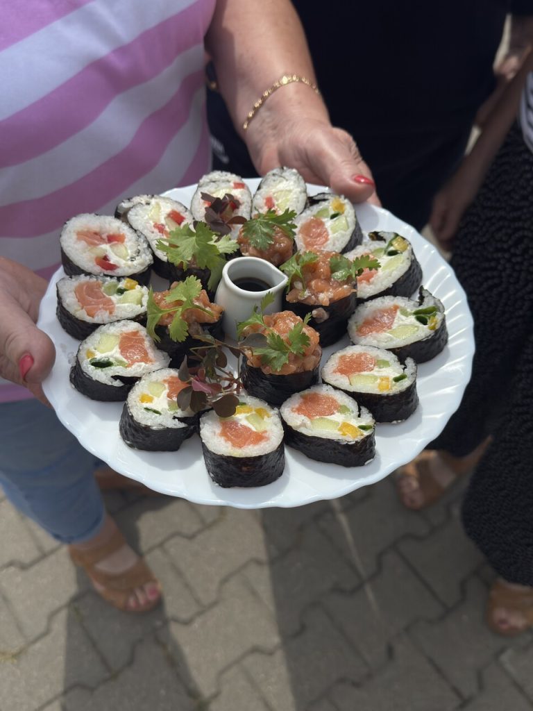 Talerz sushi z różnorodnymi składnikami, podany z sosem sojowym i świeżymi ziołami.