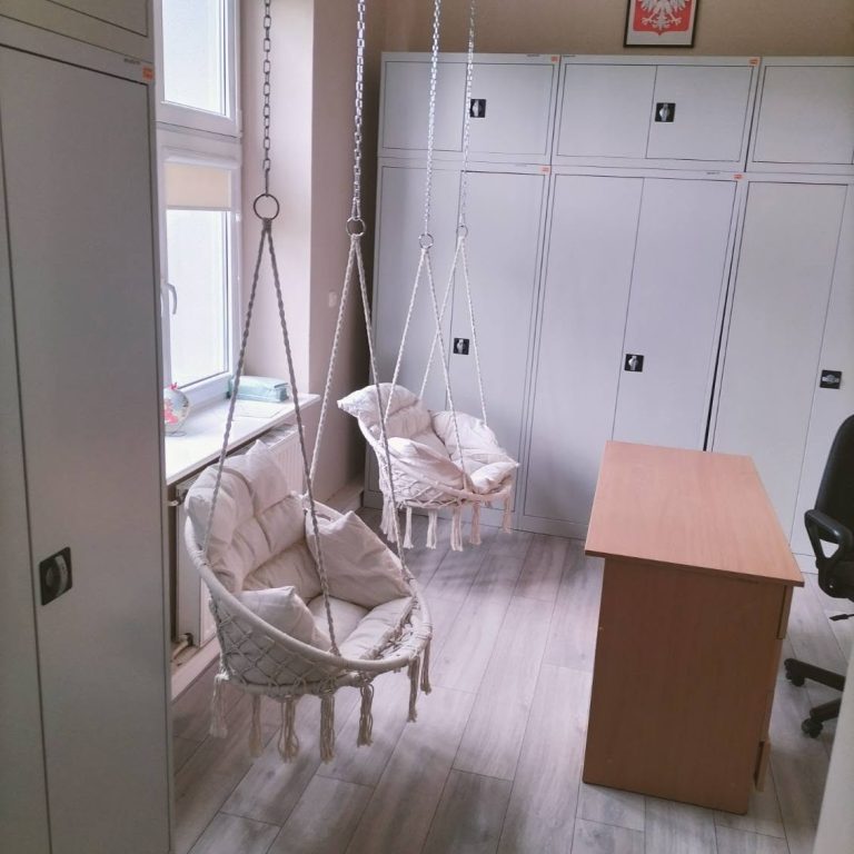 Wnętrze biura z wiszącymi fotelami i biurkiem, zapewniające komfortową przestrzeń do pracy i relaksu.